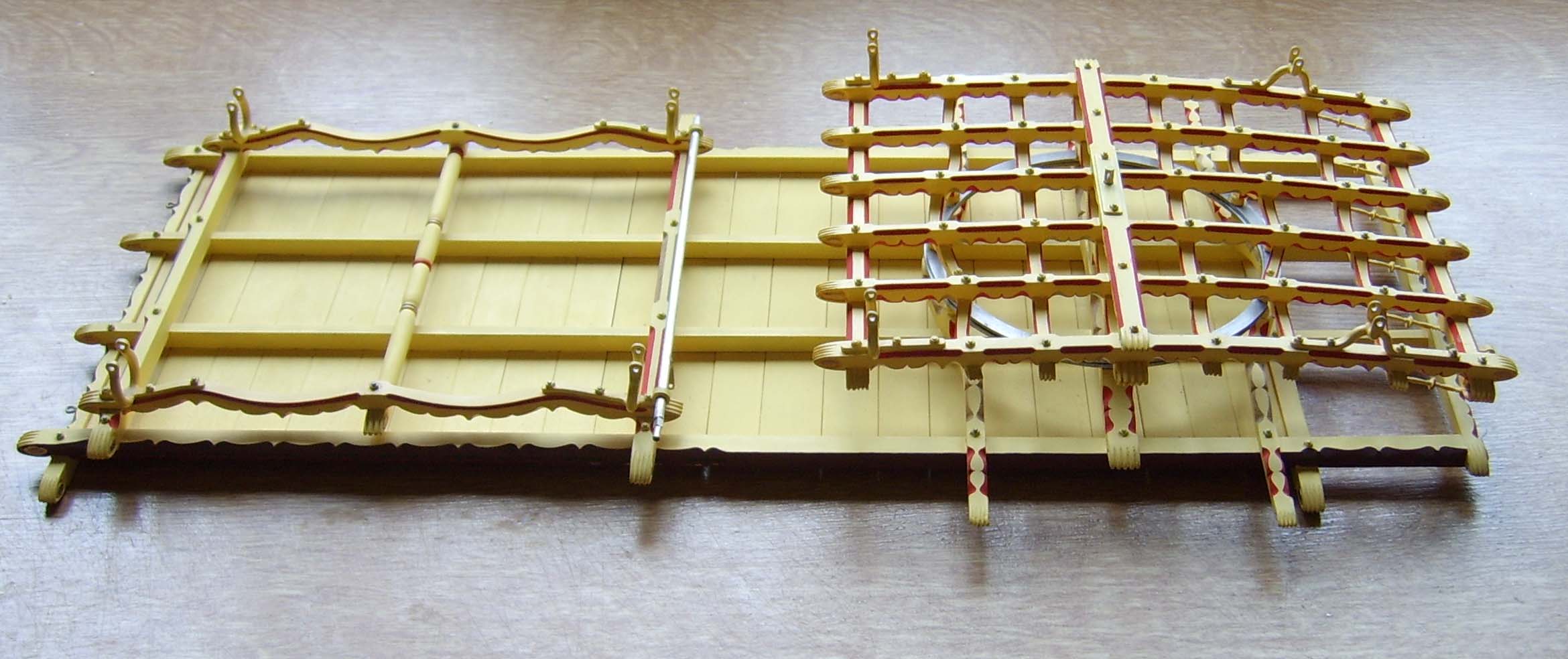 This is a view of the underside of the body (upturned) of the Ledge Waggon. The bearing plate of the forecarriage is placed in position on the bearing plate of the body. There is a lot of intricate carving and painting on both the body and forecarriage. 
